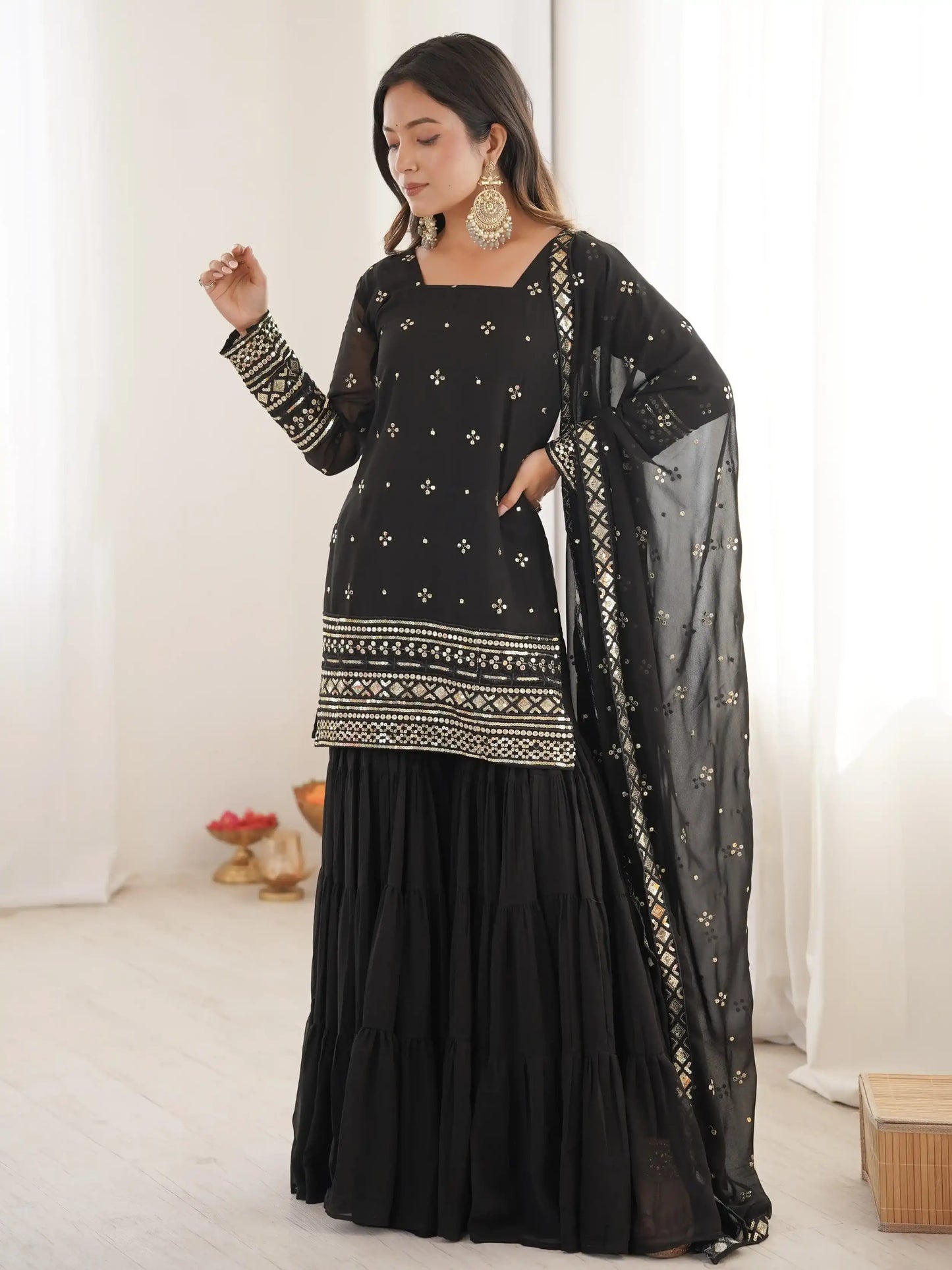 Woman wearing a black traditional outfit with intricate patterns on a white background