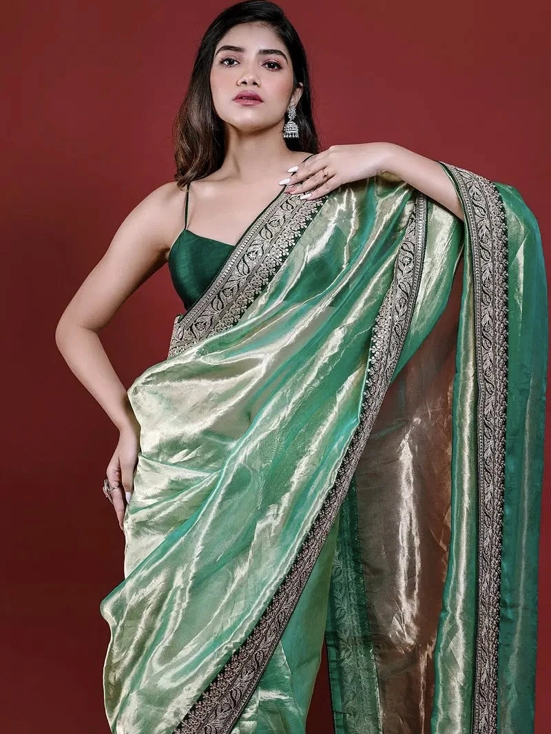 Woman wearing a green saree with a red background