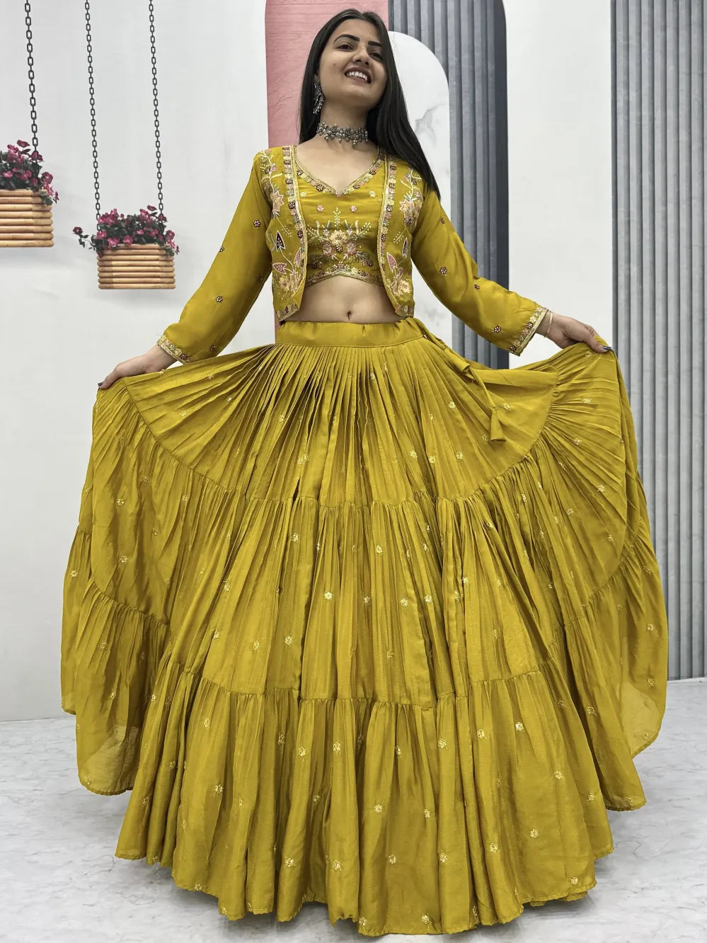 Woman wearing a mustard yellow traditional outfit with a matching skirt in a minimal indoor setting.