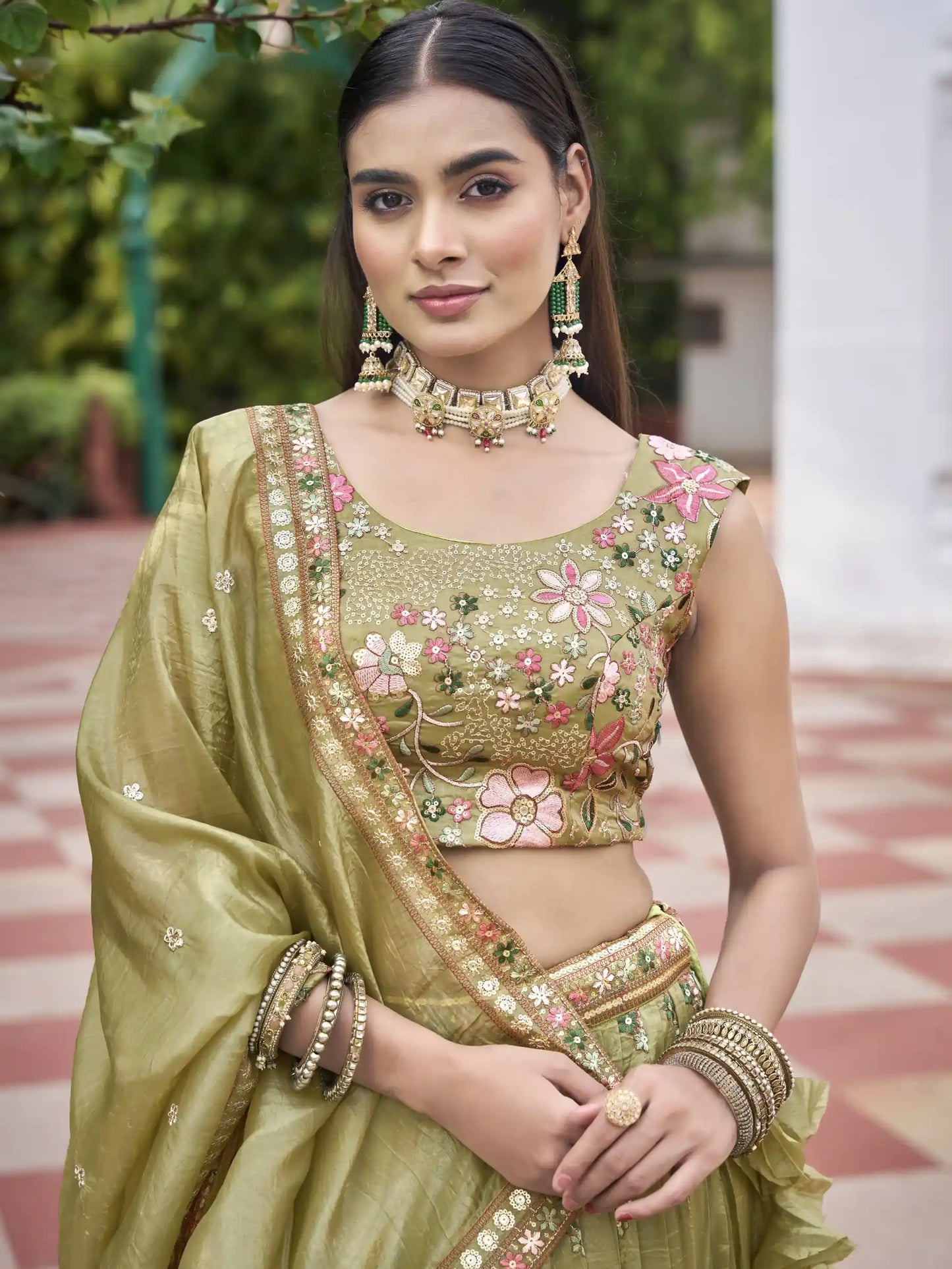 Woman in traditional green embroidered outfit with floral patterns