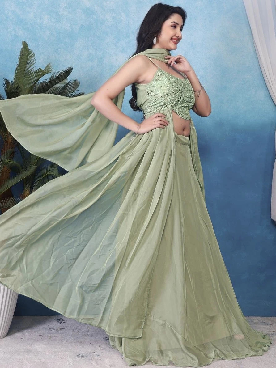 Woman wearing a light green saree with a matching blouse against a blue background