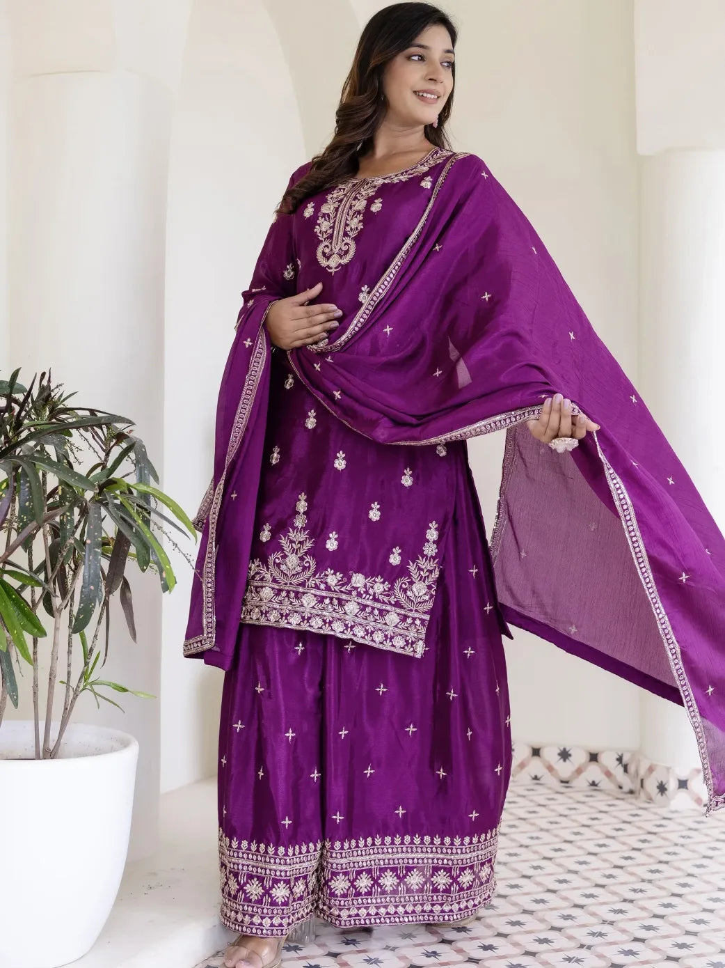 Woman wearing a purple embroidered traditional outfit with a white background