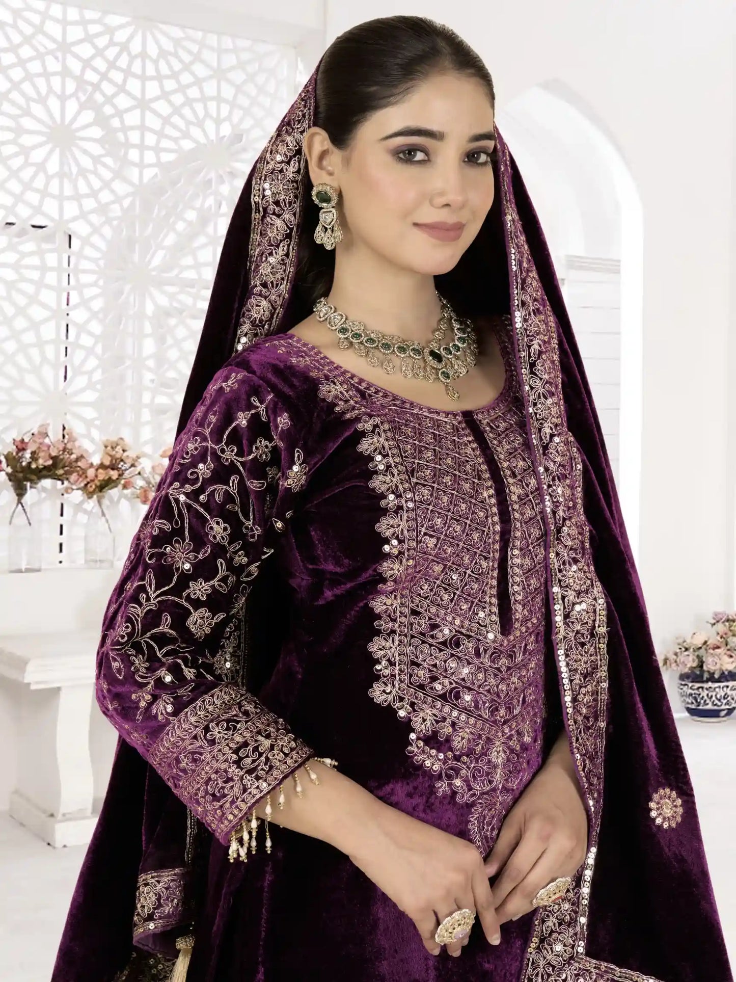 Woman wearing a purple embroidered traditional outfit with a matching dupatta.