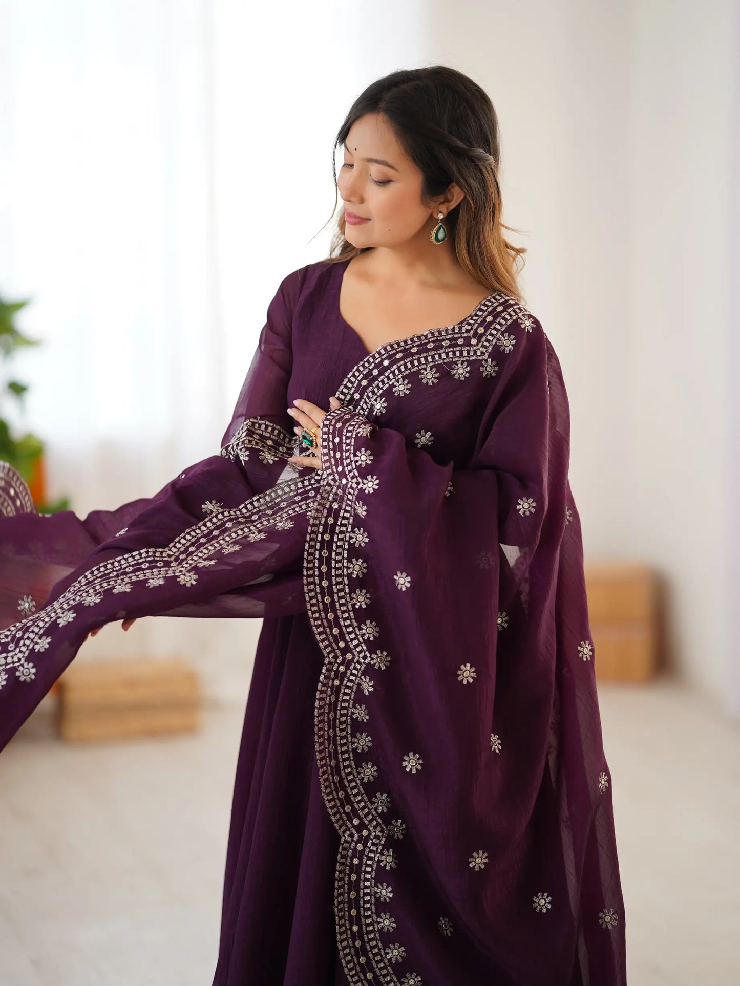 Woman wearing a purple embroidered dress in a bright room