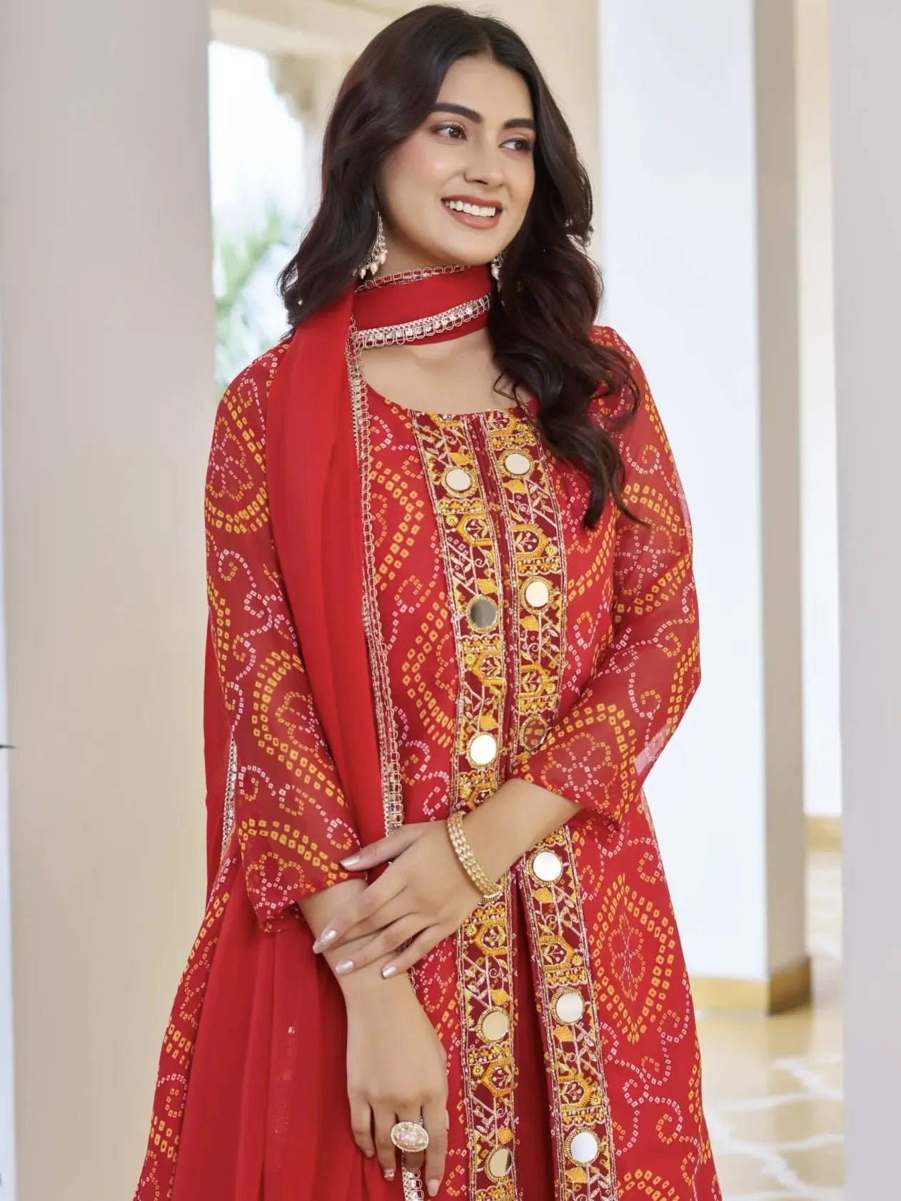 Woman wearing a red embroidered traditional outfit with gold details indoors.