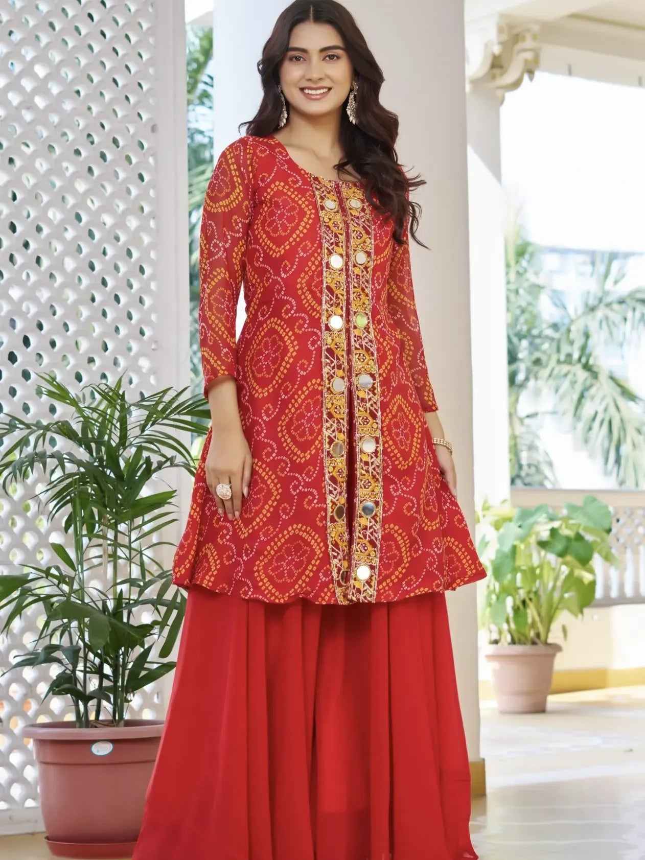 Woman wearing a red traditional outfit with intricate patterns in an outdoor setting.