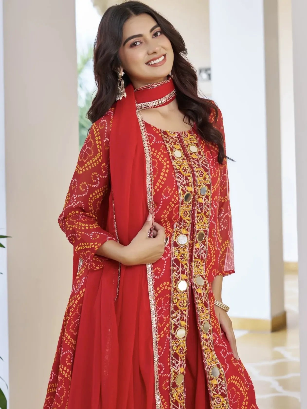 Woman wearing a red traditional outfit with gold embroidery indoors.