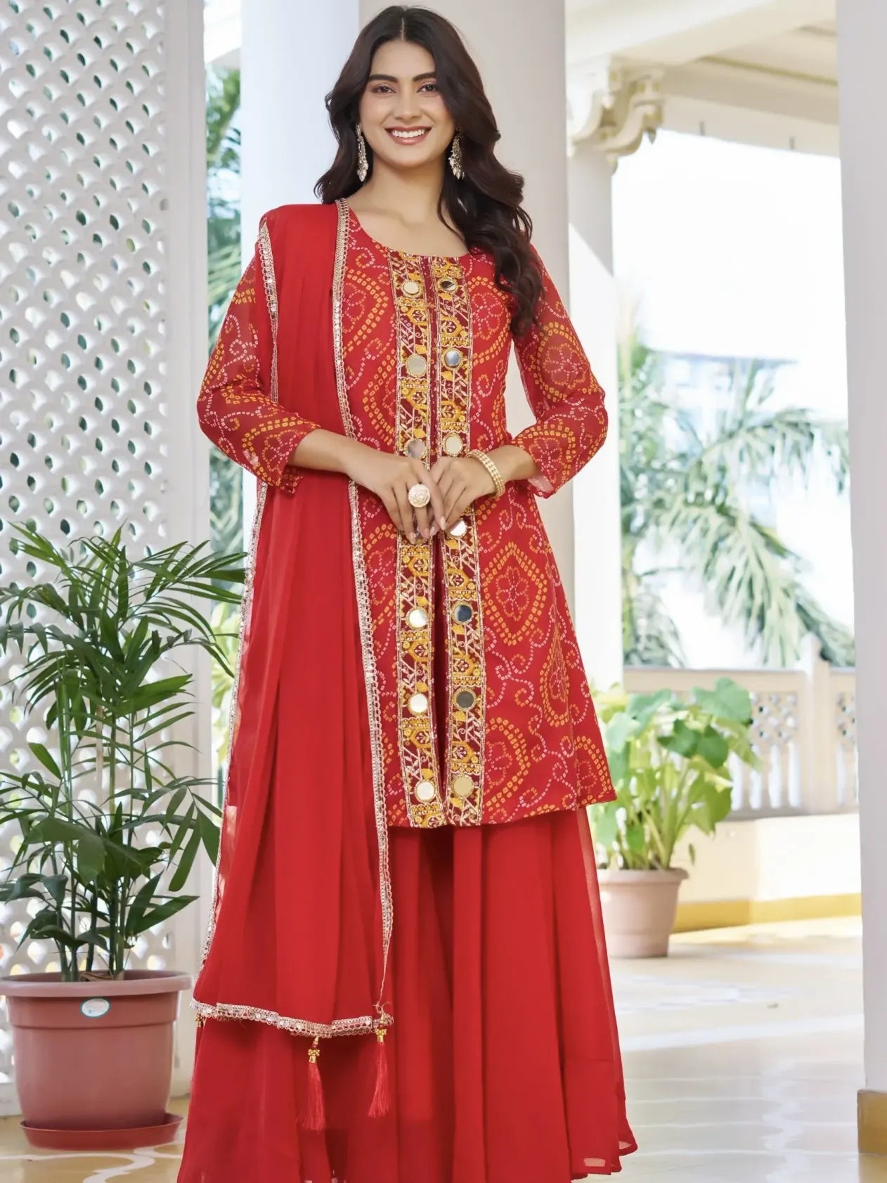 Woman wearing a red traditional outfit with gold embroidery in an indoor setting.