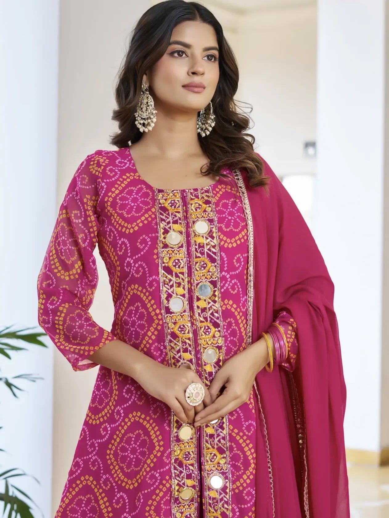 Woman wearing a pink embroidered traditional outfit with a dupatta.