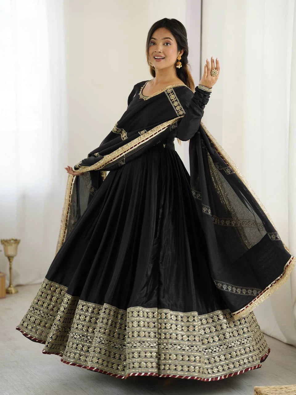 Woman wearing a black and gold traditional outfit with a white background