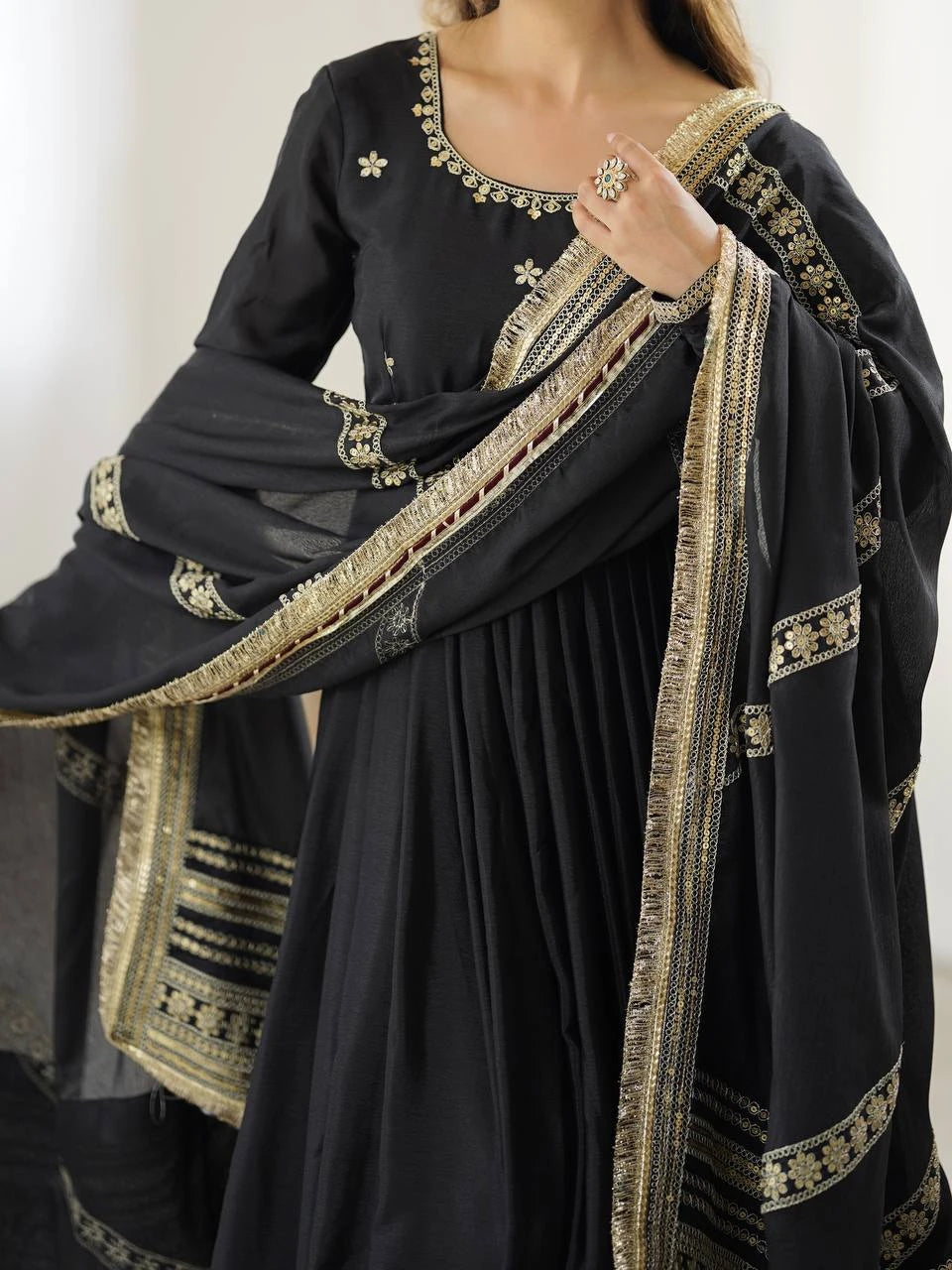 Black traditional outfit with gold embroidery on a plain background