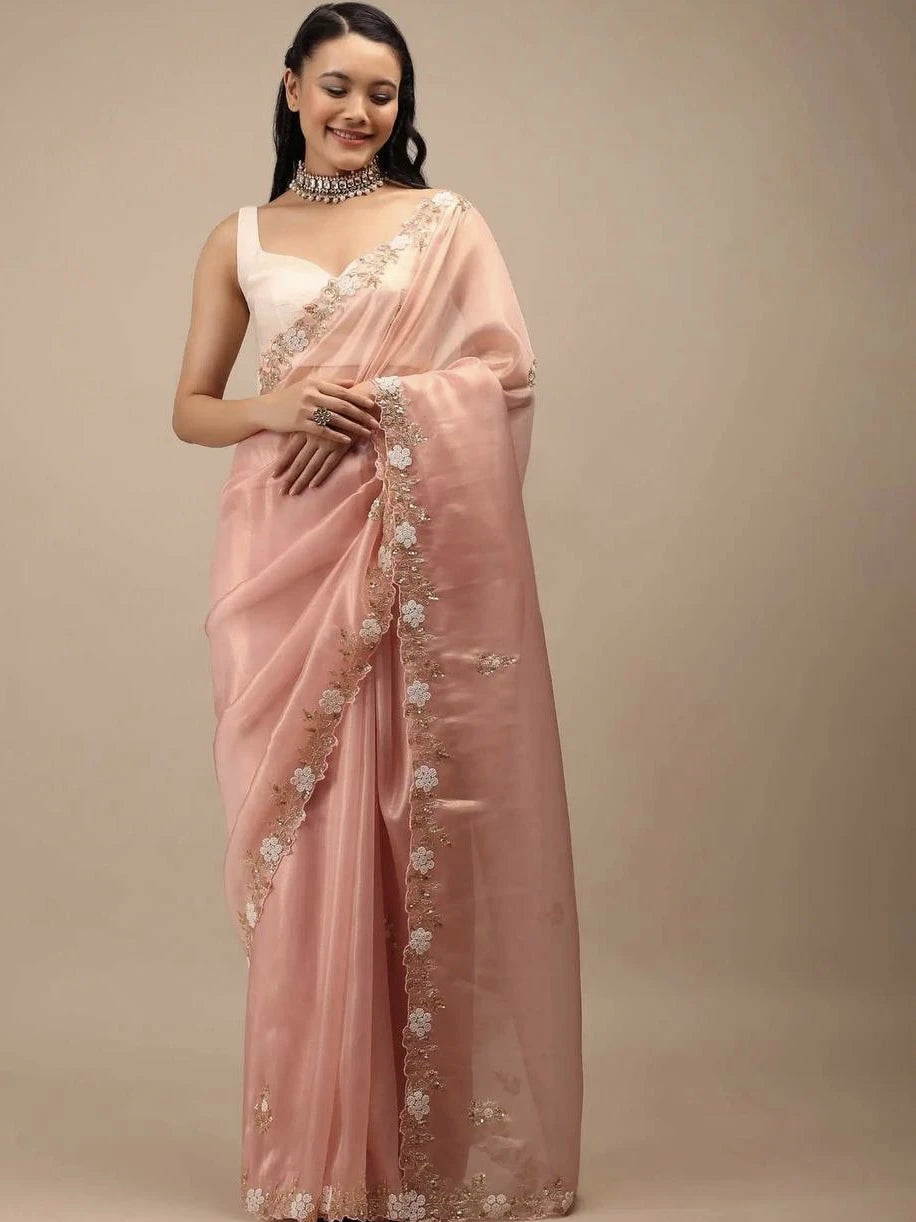 Woman wearing a pink saree with floral embroidery on a beige background