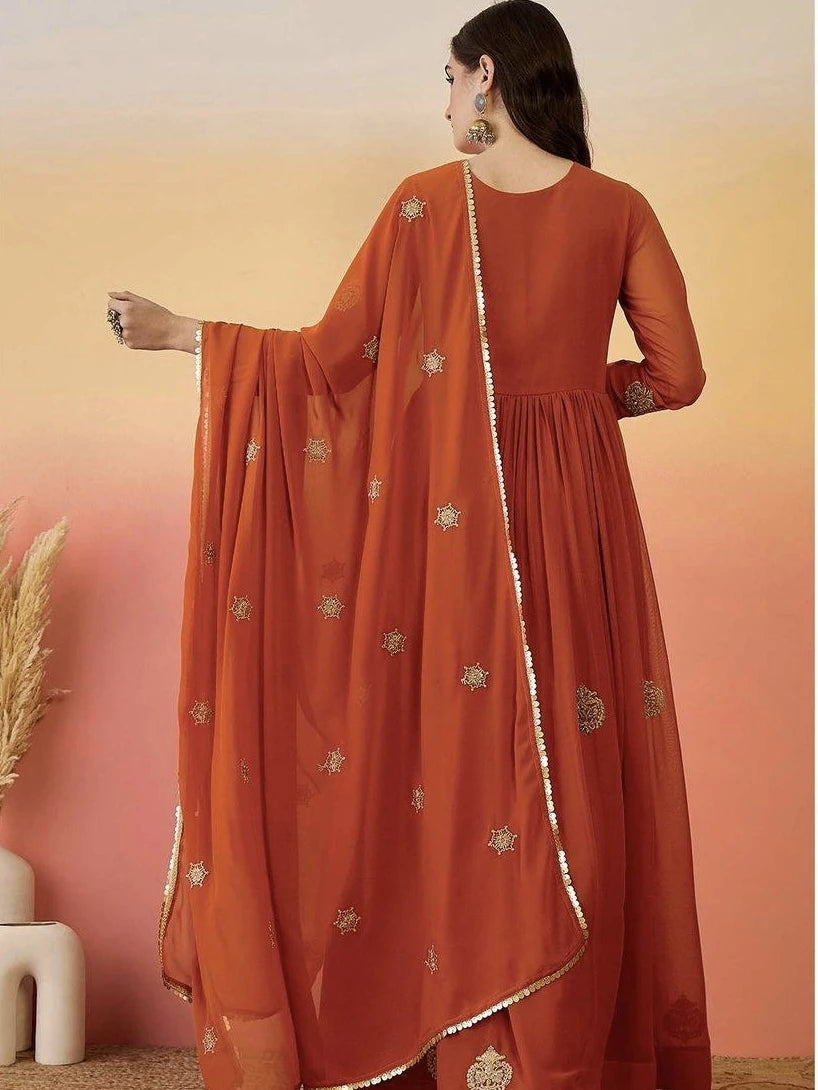 Woman wearing a rust-colored traditional outfit with embroidery against a gradient background