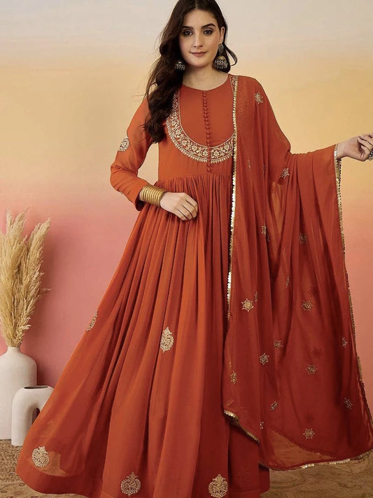 Woman wearing a rust-colored traditional outfit with gold embroidery against a gradient background