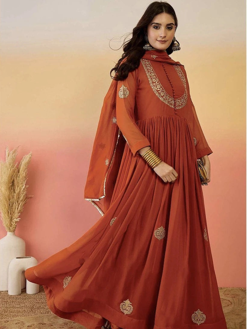 Woman wearing an orange traditional outfit with gold embroidery against a warm gradient background