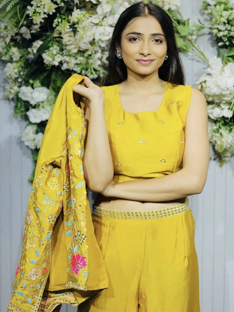 Woman in a yellow traditional outfit with a floral shawl against a white floral background