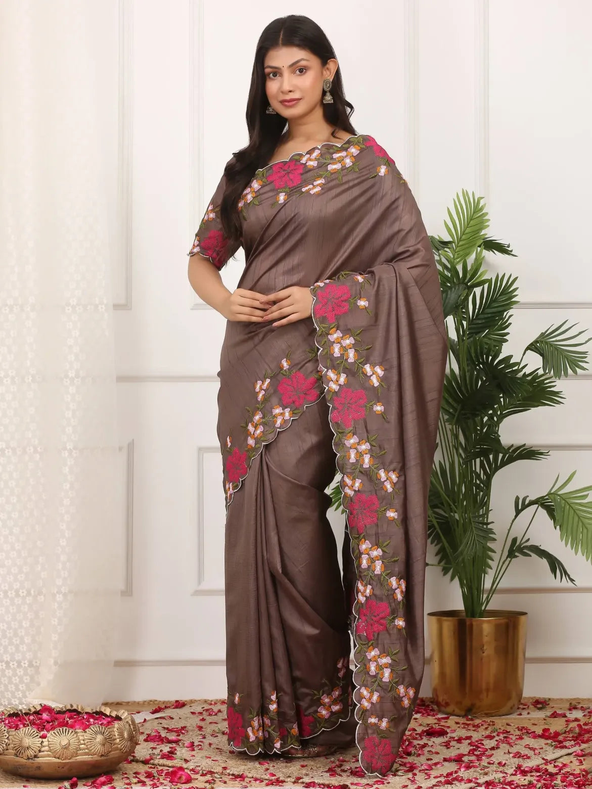 Woman wearing a brown saree with floral patterns in a decorated indoor setting