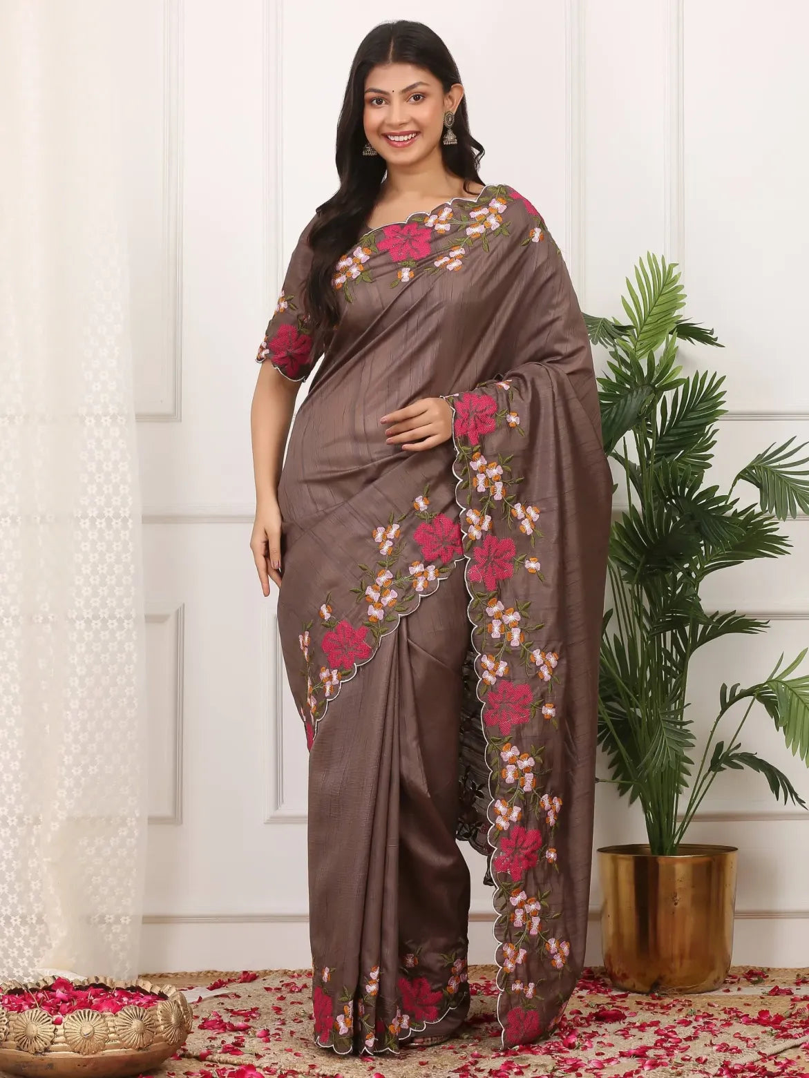 Woman wearing a brown saree with floral patterns in a decorated indoor setting