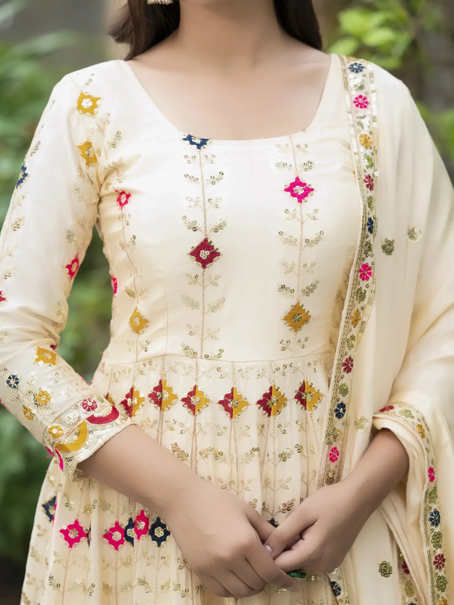 Beige dress with floral embroidery on a blurred green background