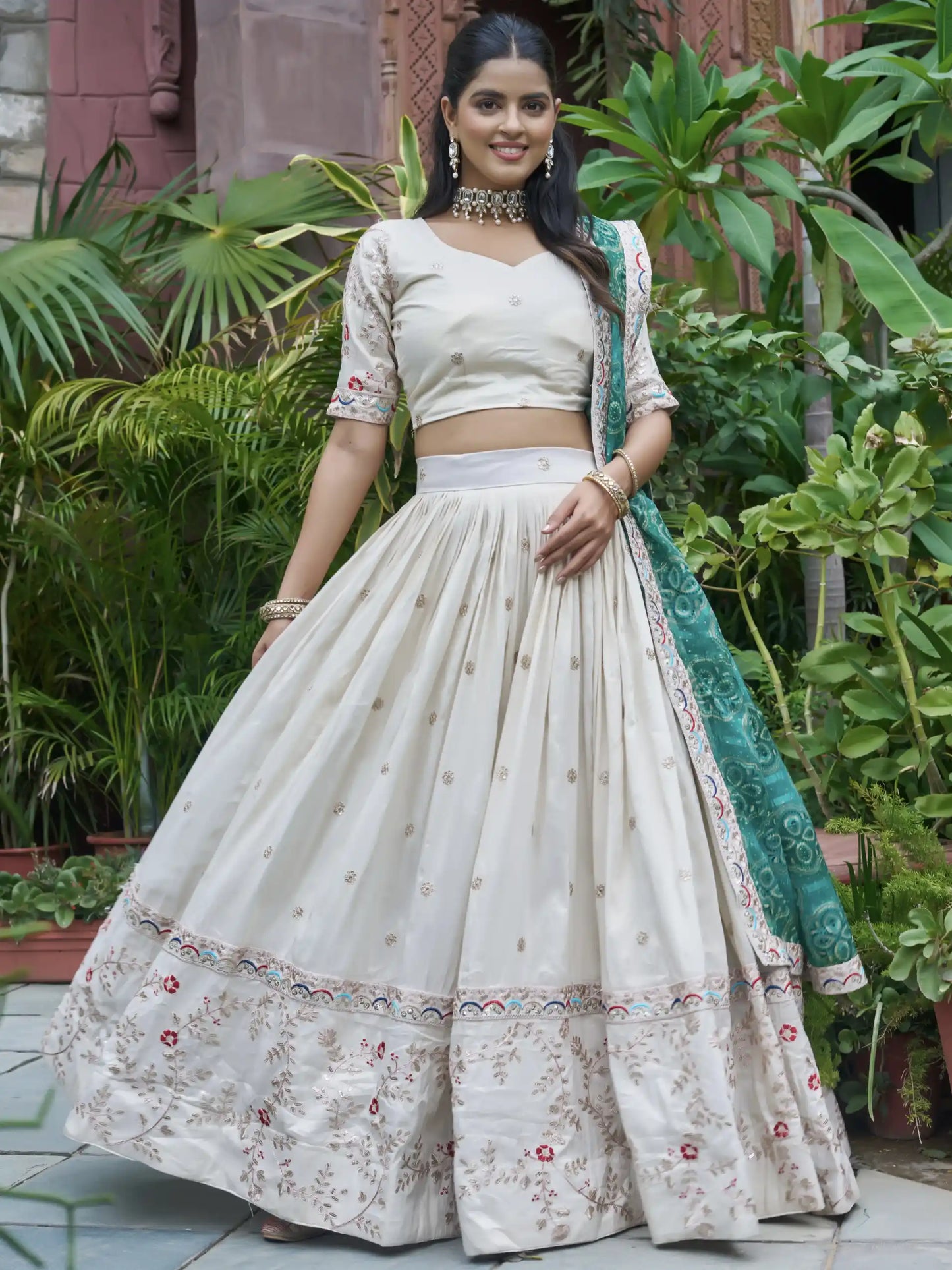 Woman in a traditional outfit with a green dupatta standing in a garden.