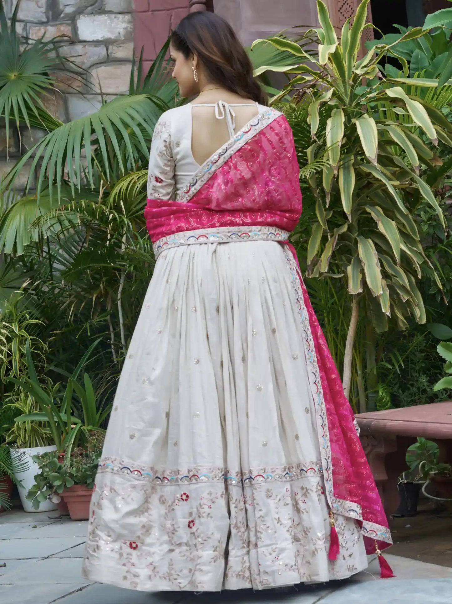 Woman wearing a white and pink traditional outfit with a garden background