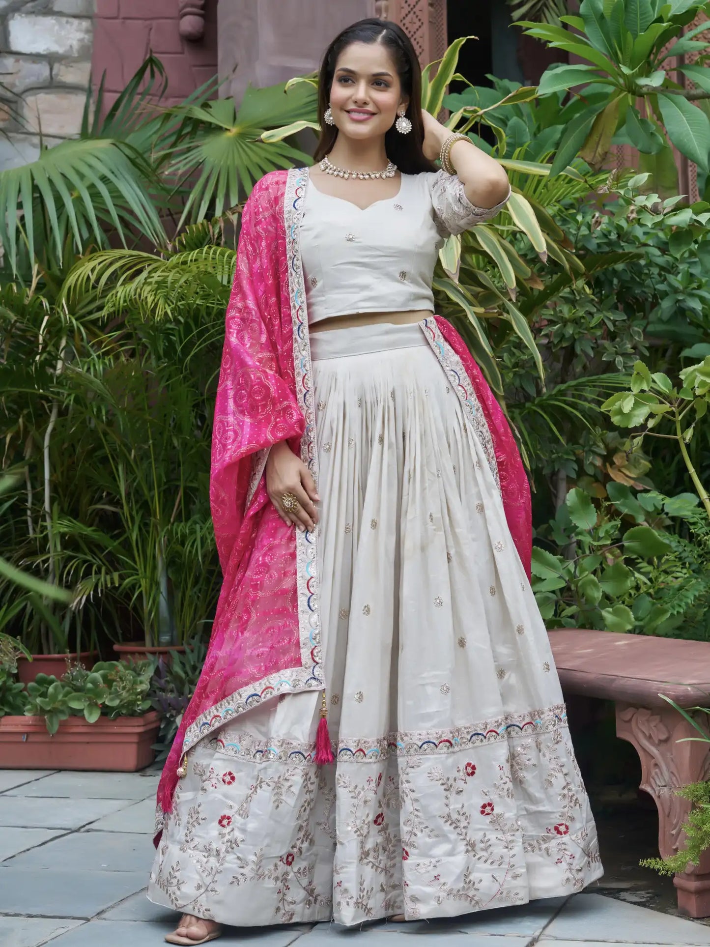 Woman in traditional outfit with pink dupatta standing outdoors