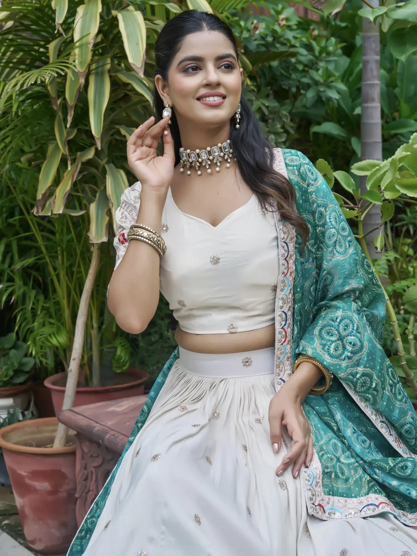 Woman in traditional outfit with green dupatta against a natural background
