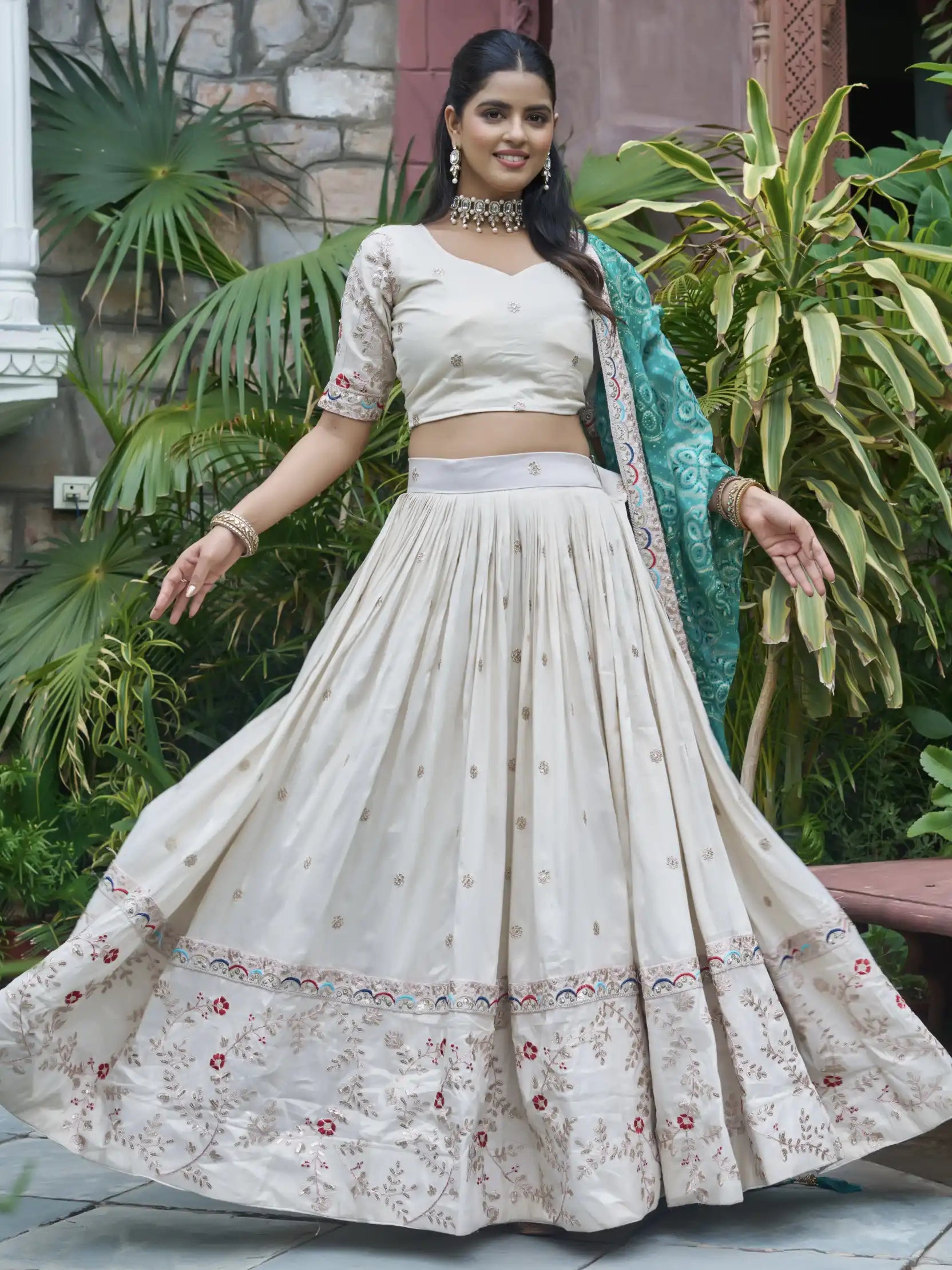 Woman in a traditional outfit with a floral skirt and blouse, standing outdoors.