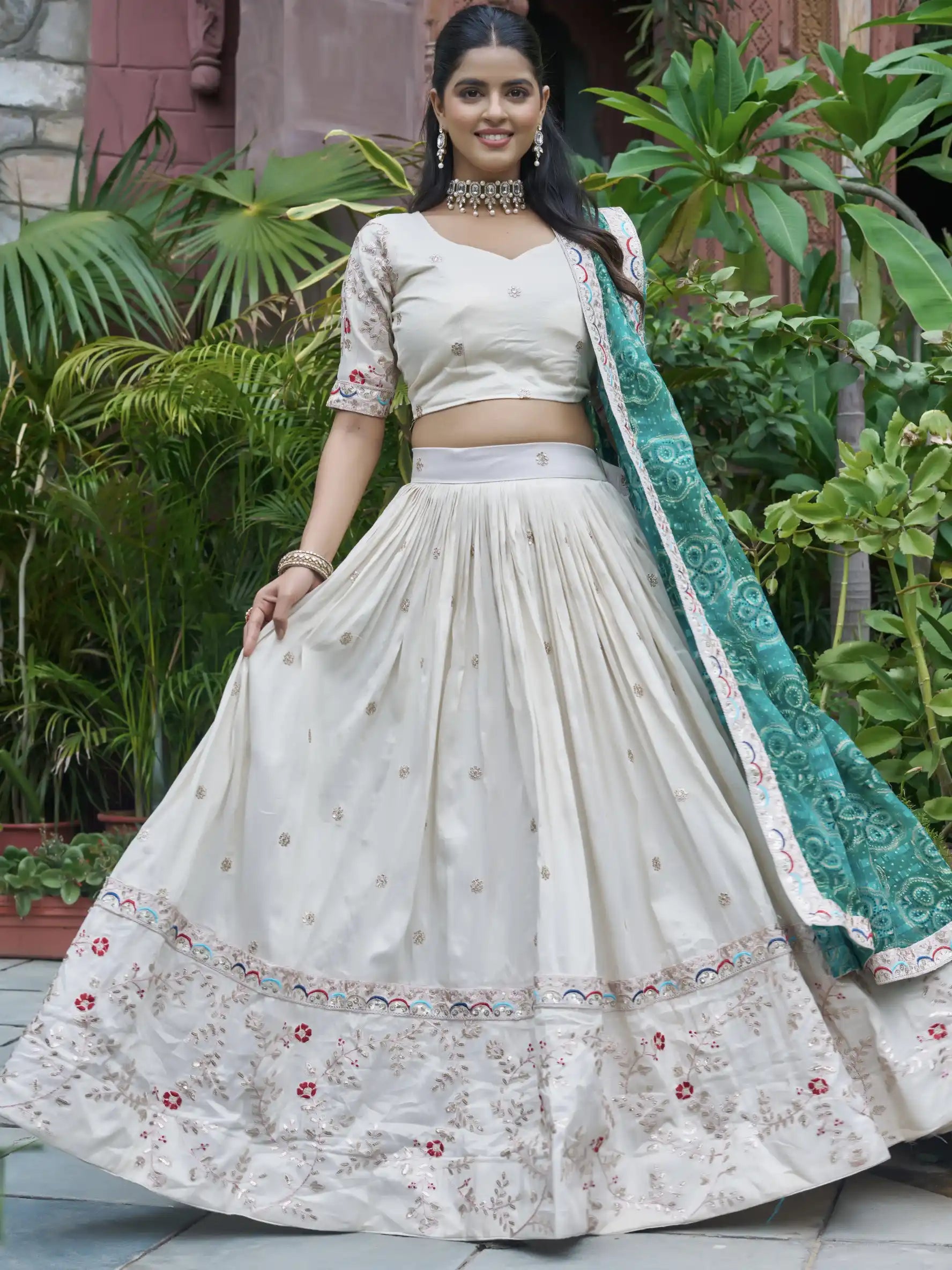 Woman in a traditional outfit with a green dupatta standing outdoors.