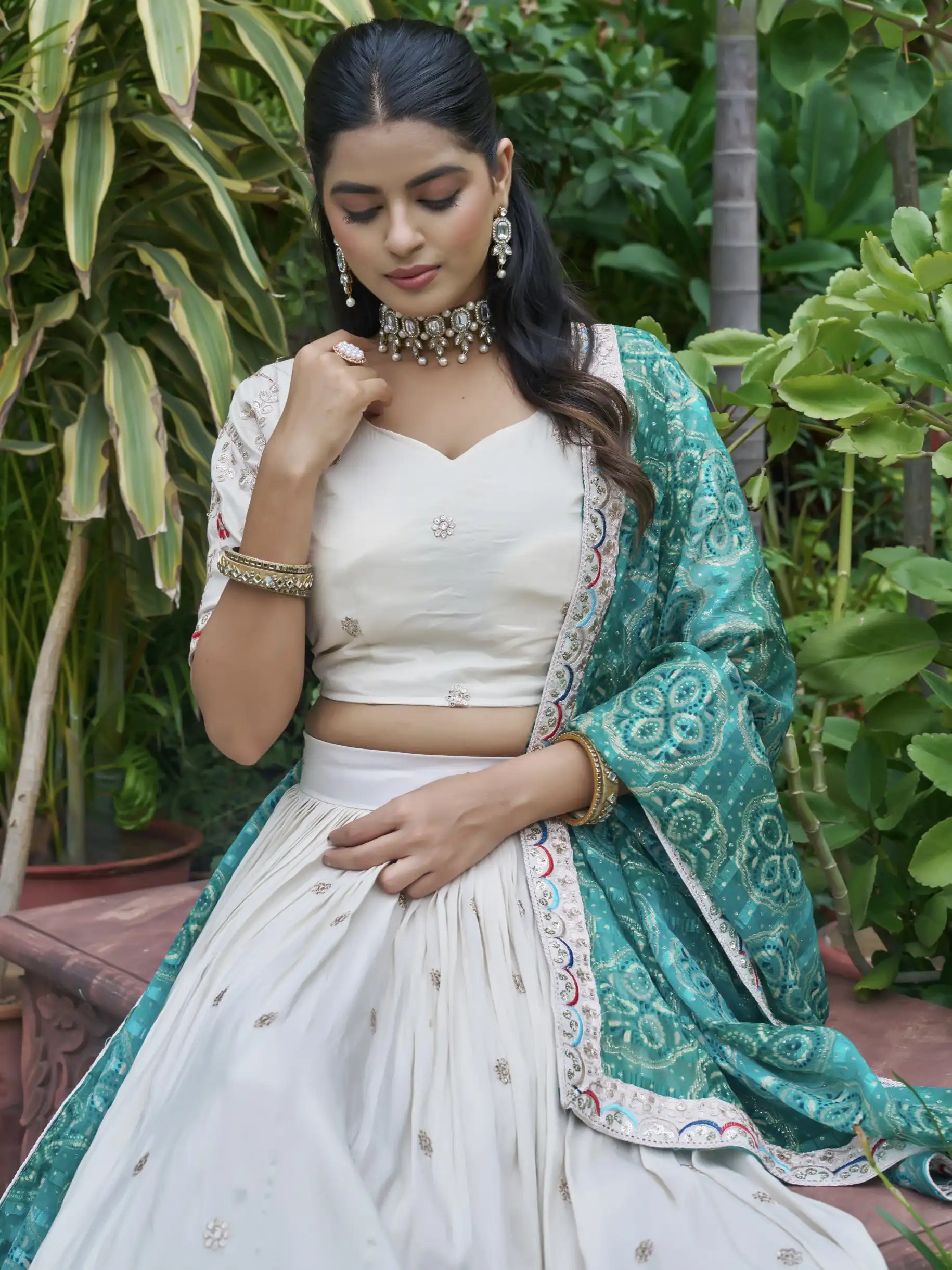 Woman in a traditional outfit with a green dupatta against a green foliage background