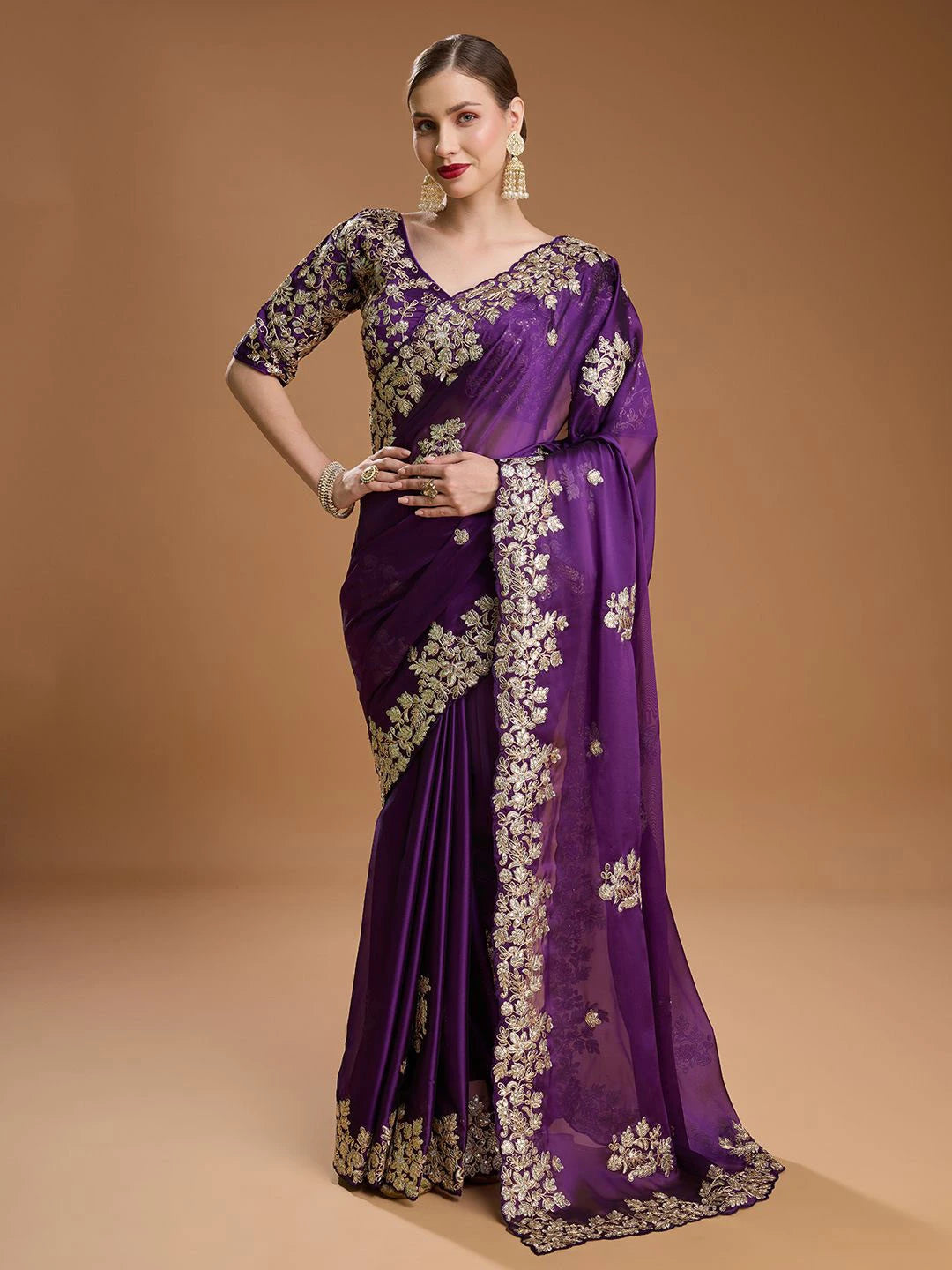 Woman wearing a purple saree with floral patterns on a brown background