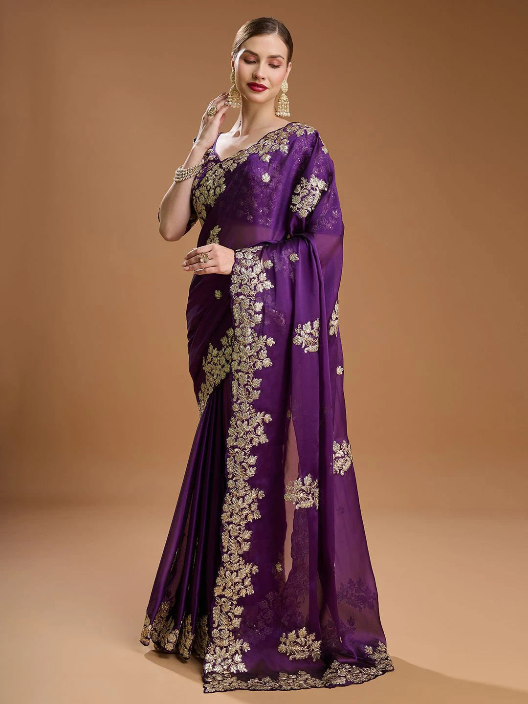 Woman wearing a purple saree with floral patterns on a beige background