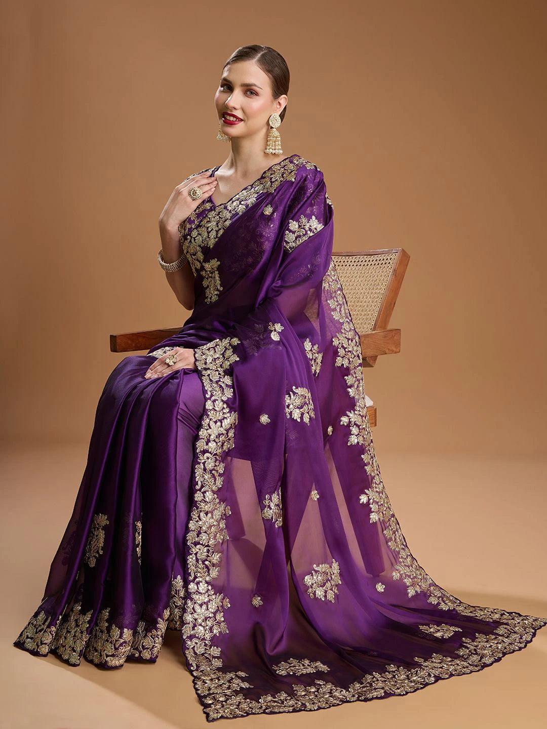 Woman wearing a purple saree with floral patterns on a beige background