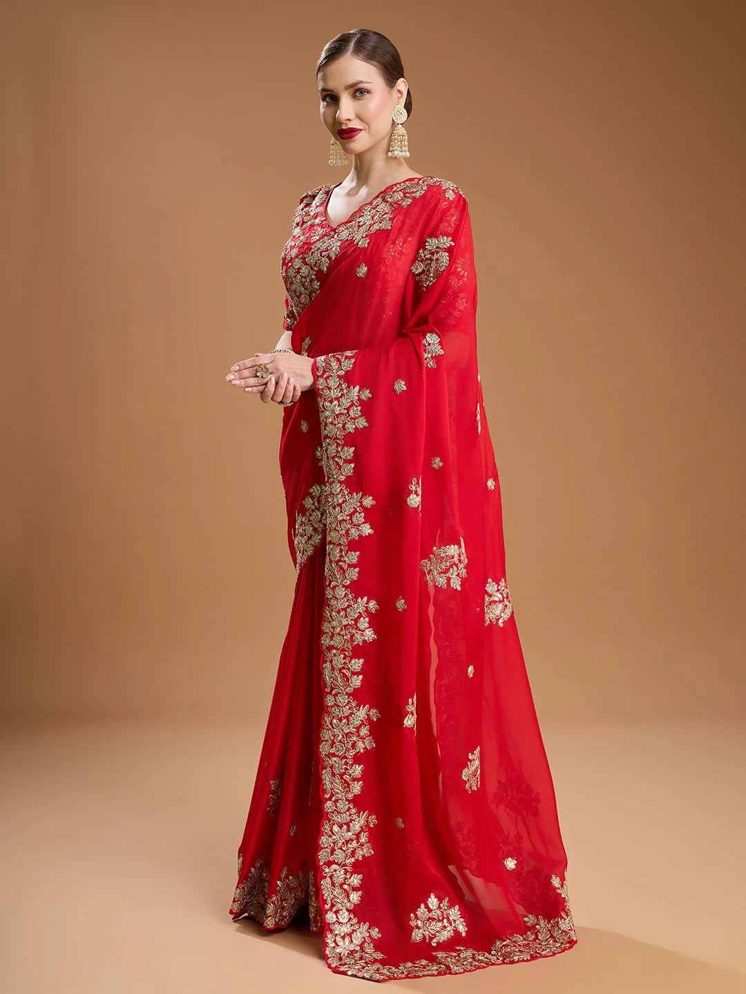 Red saree with gold embroidery on a model against a beige background