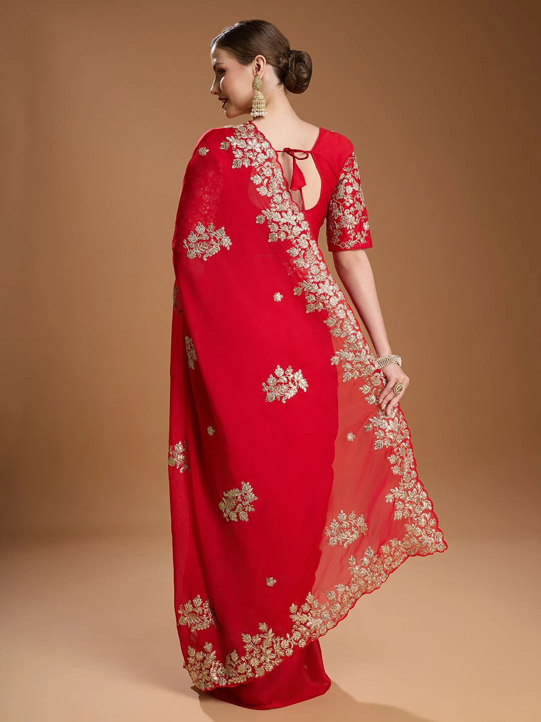 Red saree with gold embroidery on a beige background