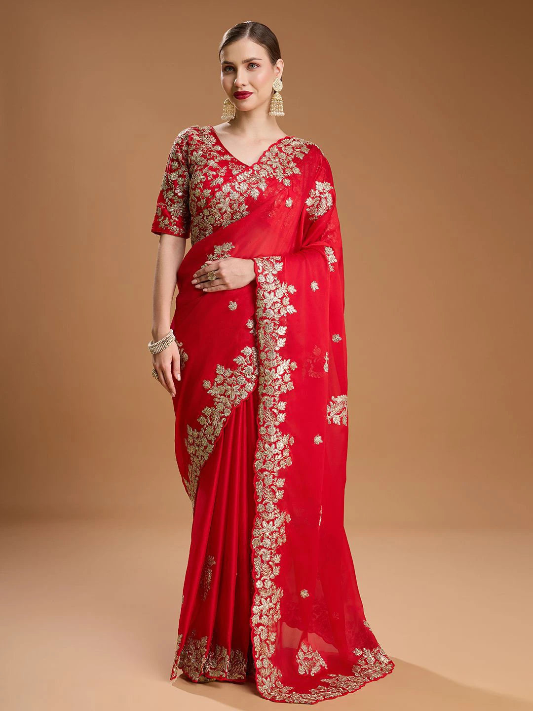Red saree with gold embroidery on a beige background