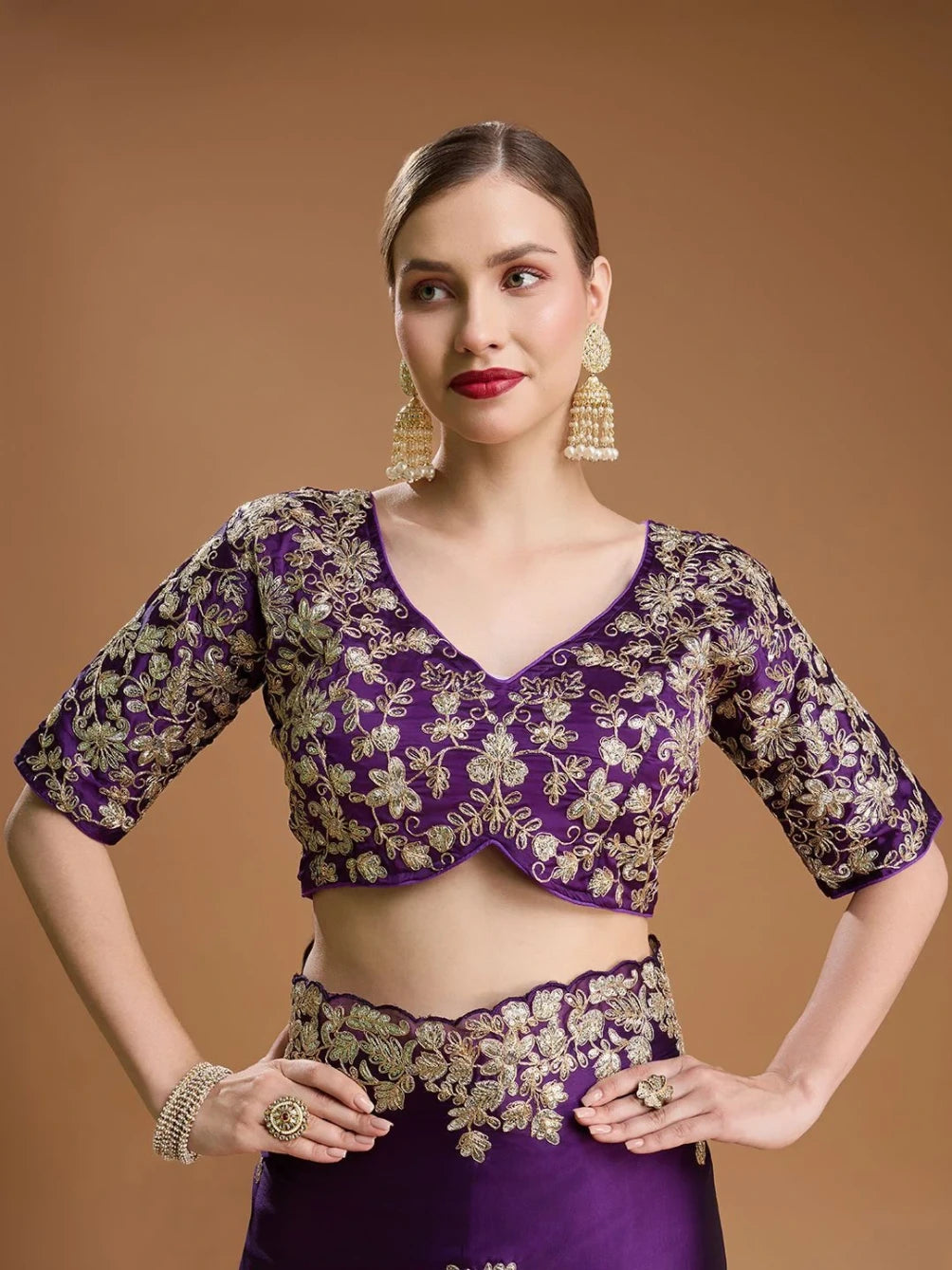 Woman wearing a purple and gold traditional outfit on a brown background