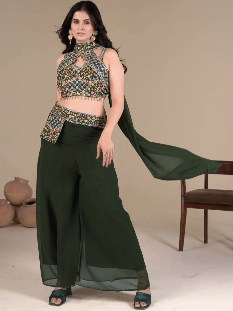 Woman wearing a traditional outfit with a patterned top and dark green pants against a neutral background.