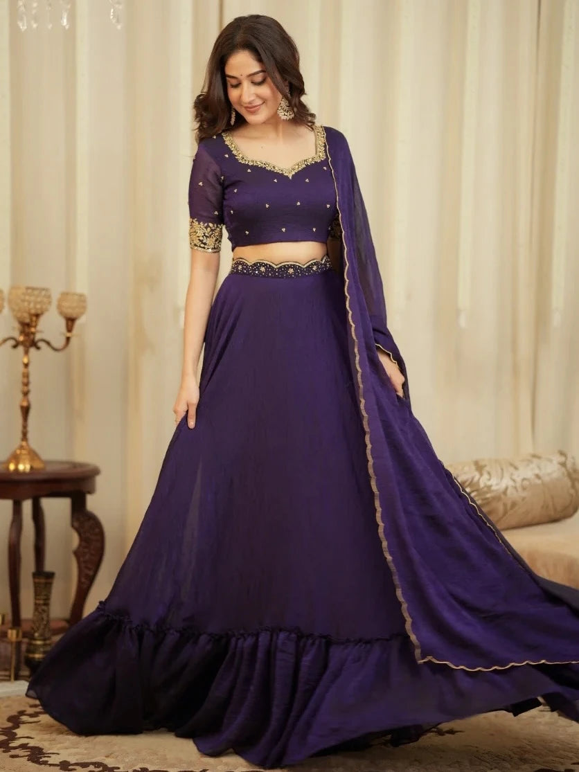 Woman wearing a purple traditional outfit with gold details against a neutral background