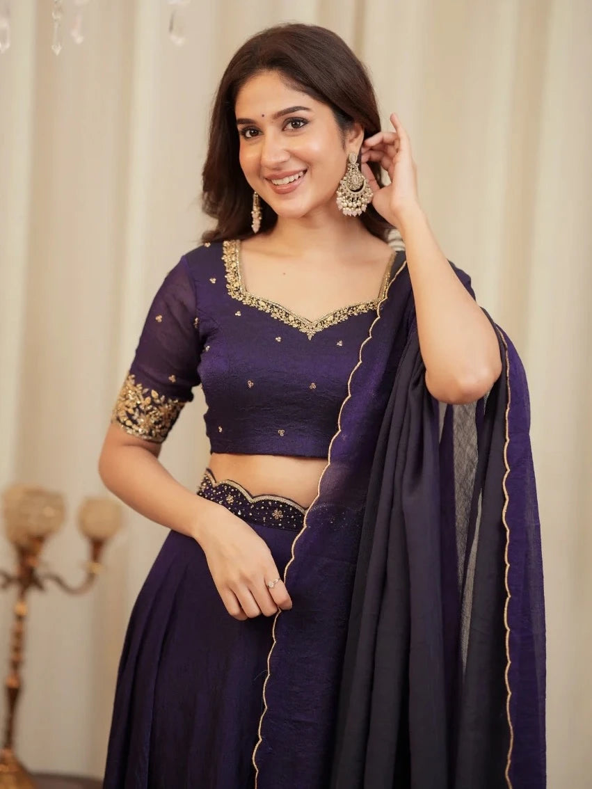 Woman wearing a purple traditional outfit with gold embroidery against a neutral background