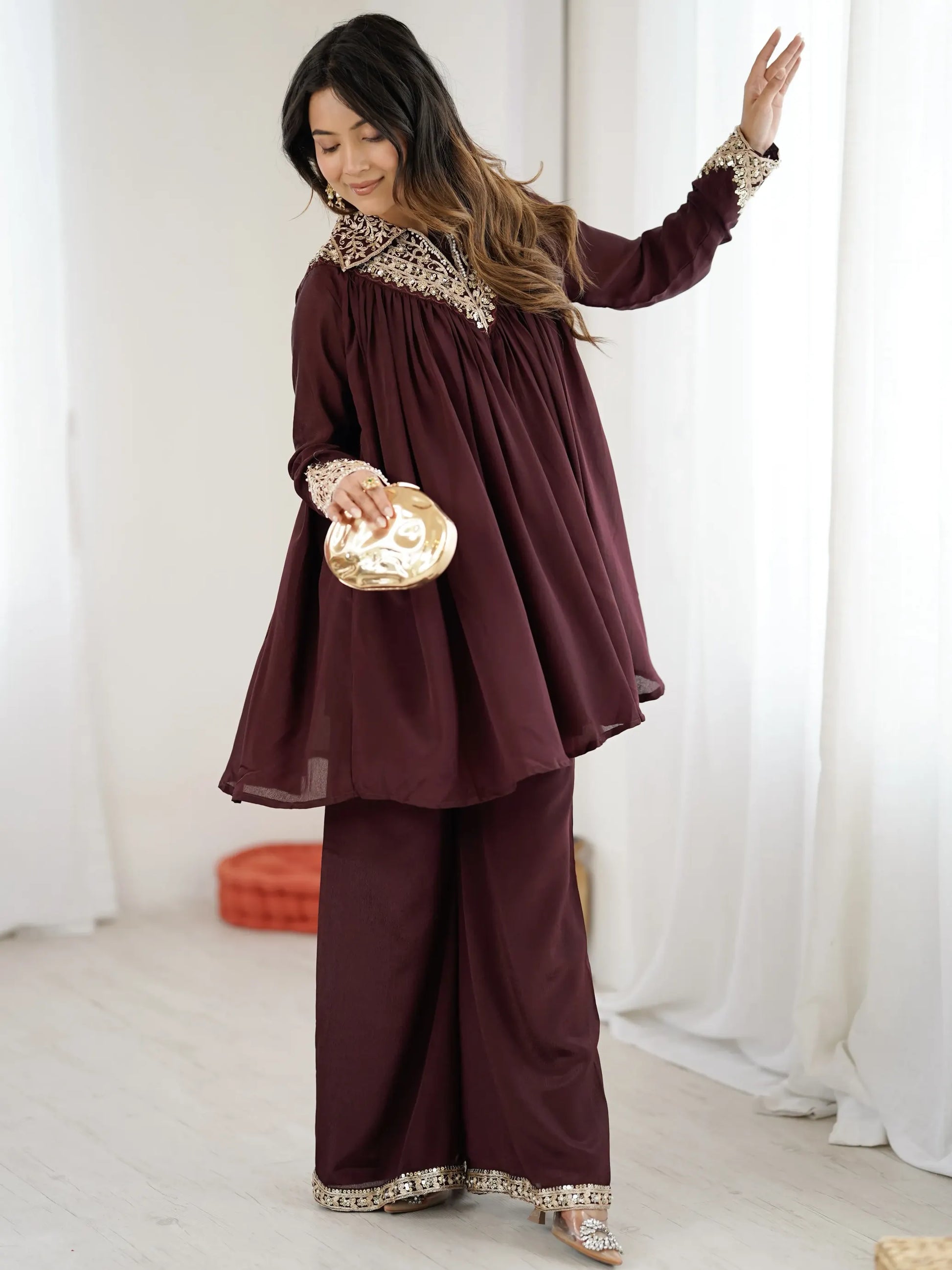 Woman wearing a burgundy outfit with lace details in a white room.