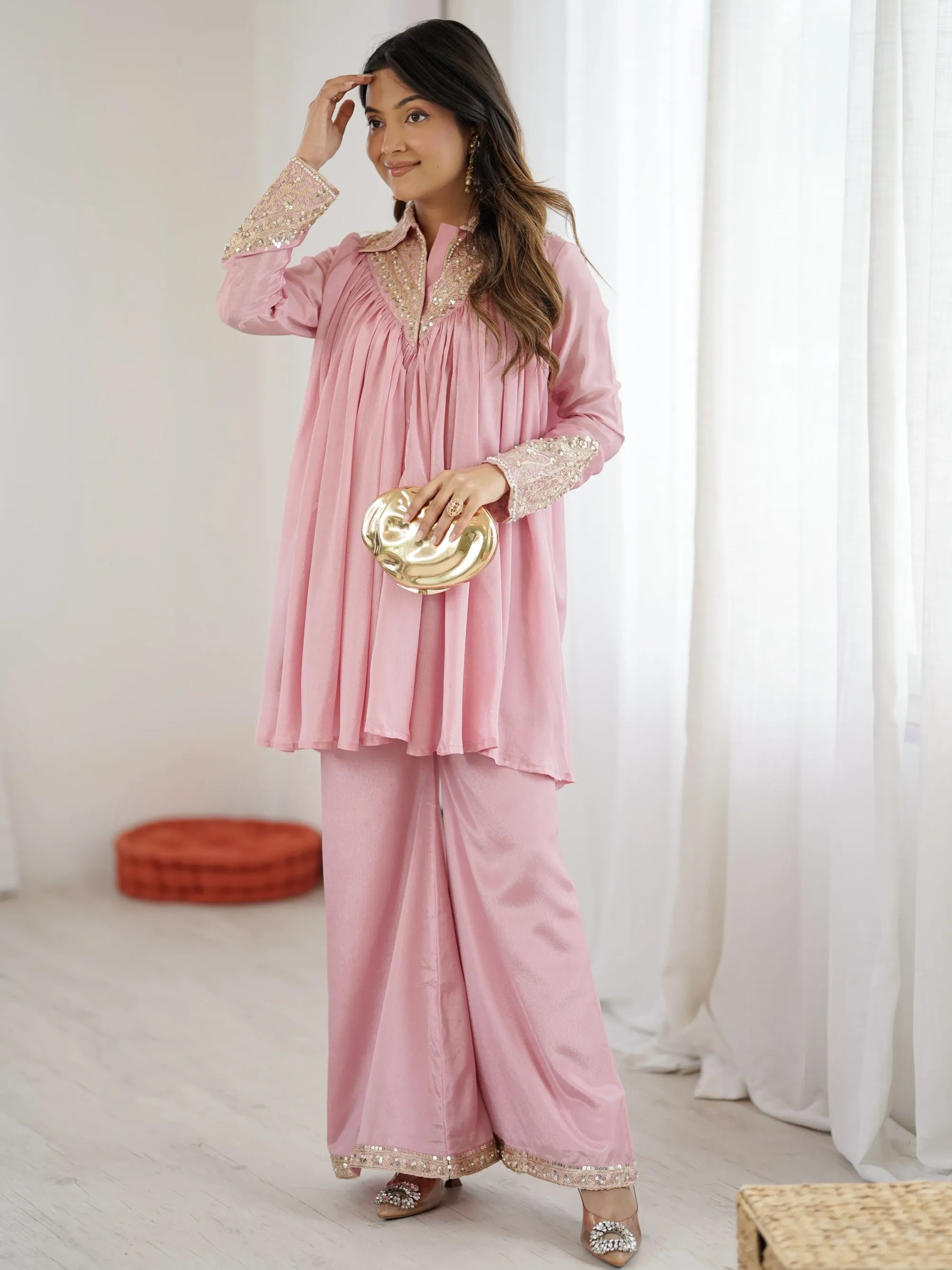 Woman wearing a pink traditional outfit with gold details indoors.