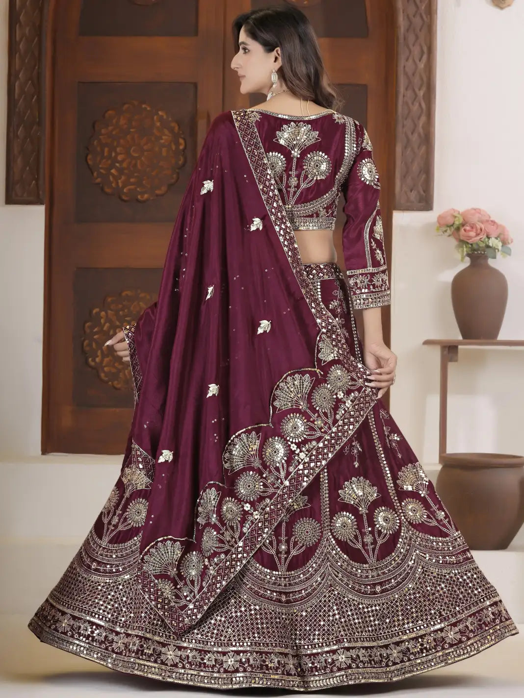 Woman wearing a maroon embroidered saree with silver details in an indoor setting.