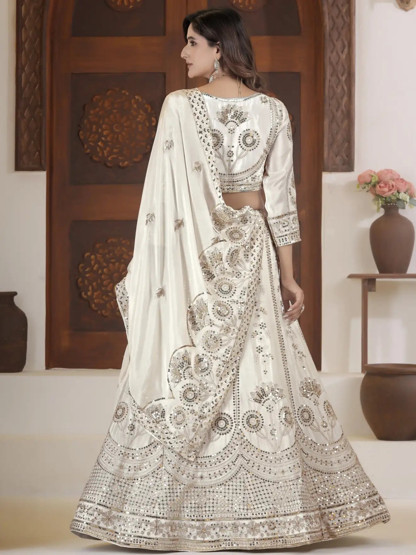 Woman wearing a white embroidered traditional outfit in an indoor setting.