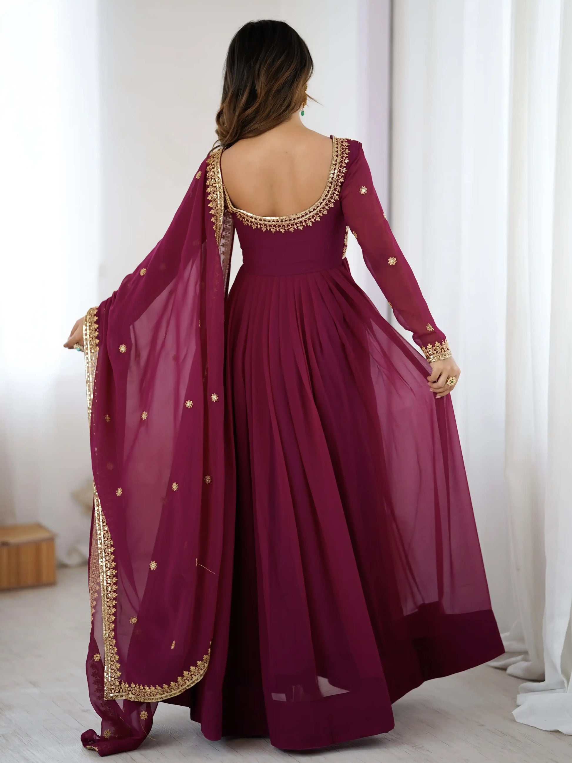 Woman wearing a burgundy saree with gold border in a room setting