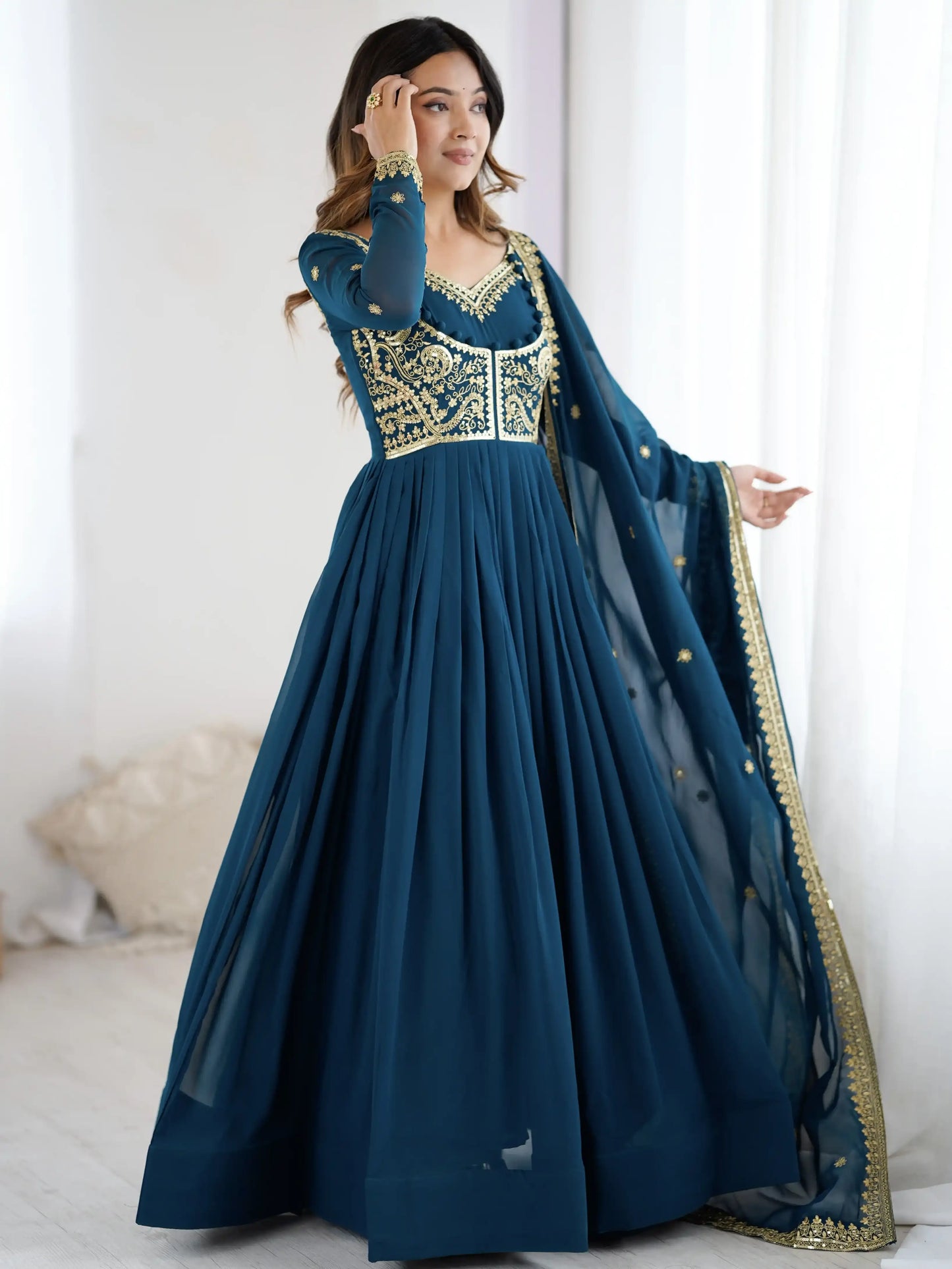 Woman wearing a blue and gold traditional outfit with a white background