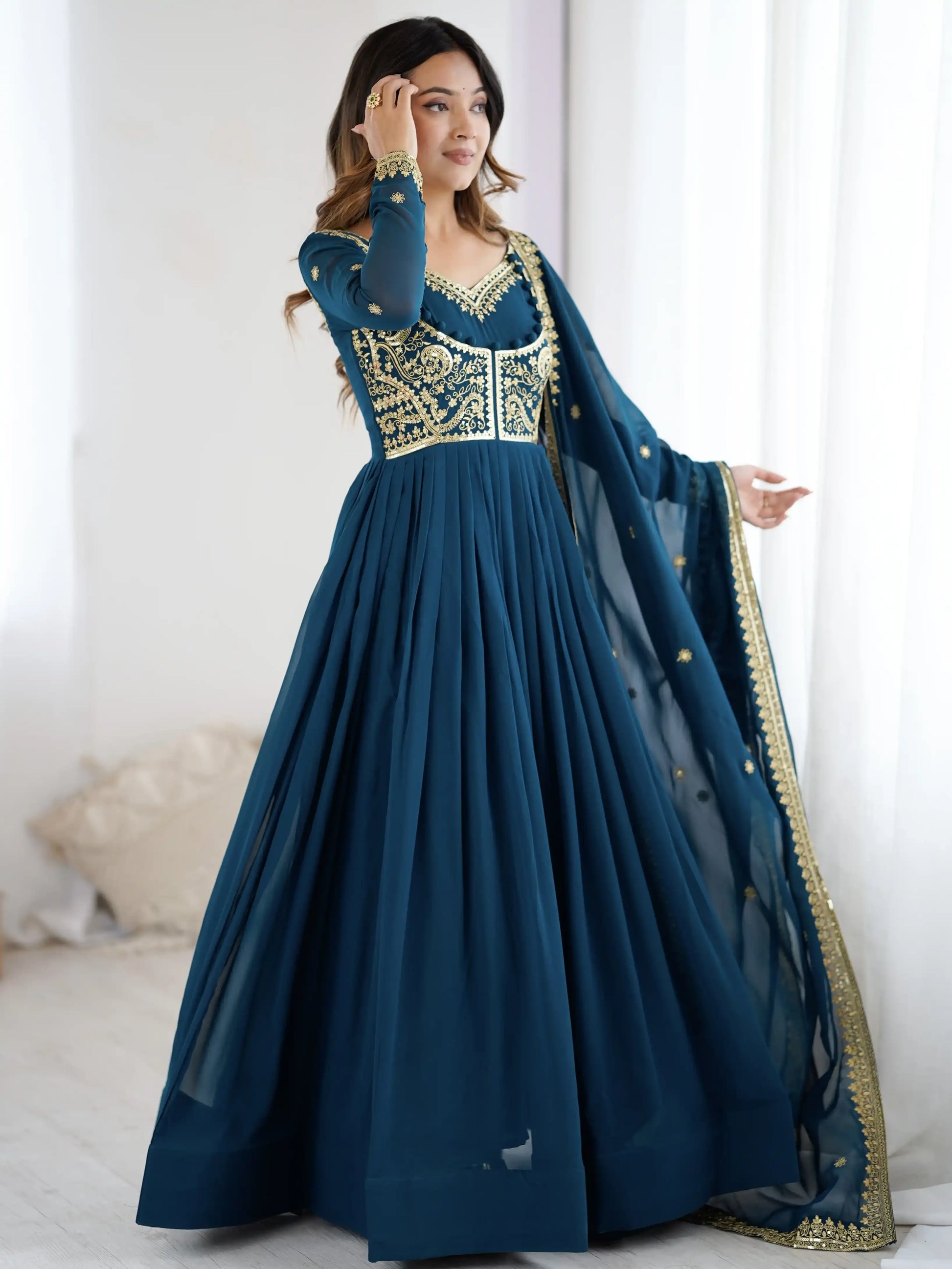 Woman wearing a blue and gold traditional outfit with a white background