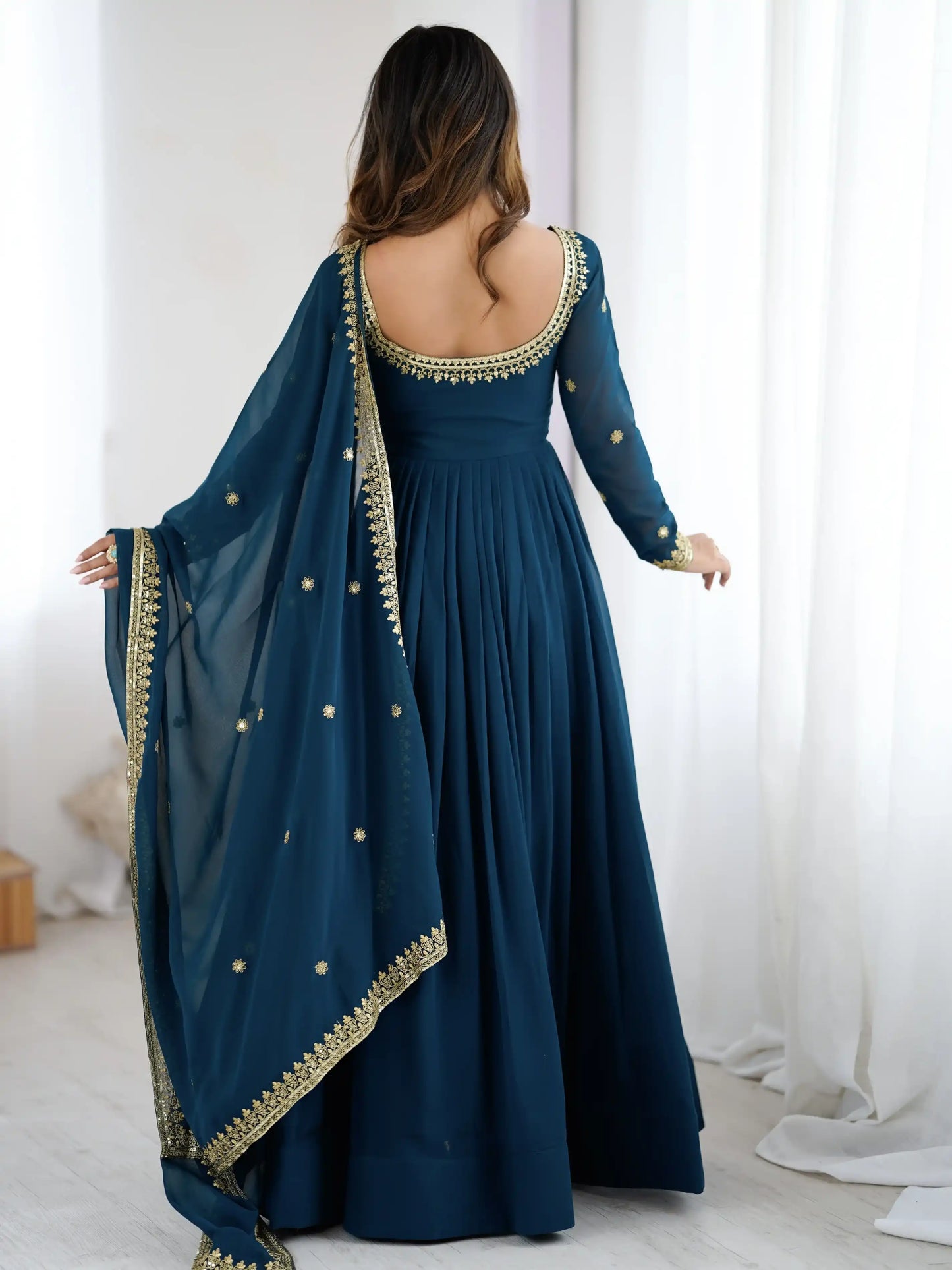 Woman wearing a dark blue dress with gold embroidery in a minimalistic setting