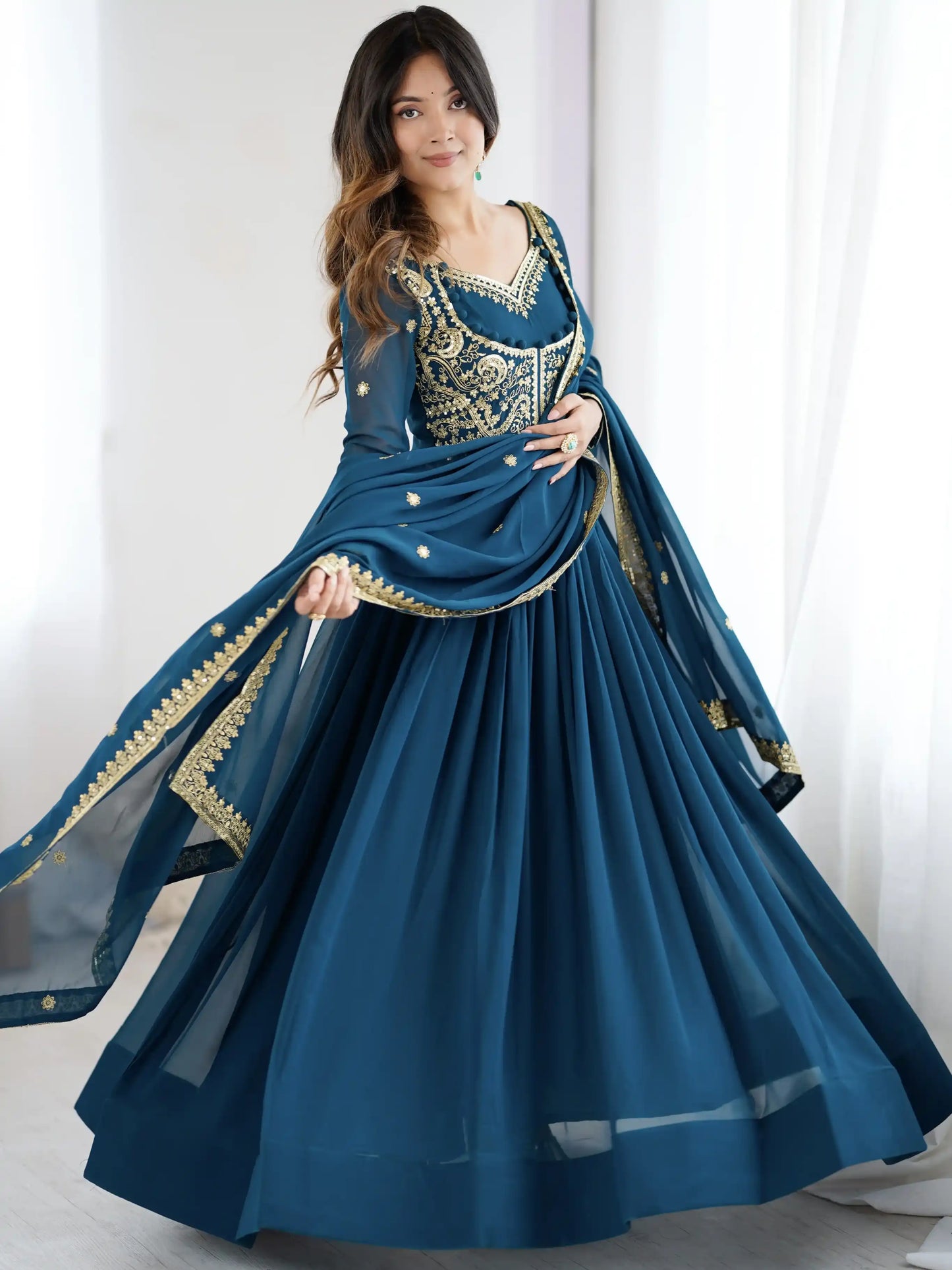Woman wearing a blue traditional outfit with gold embroidery against a white background