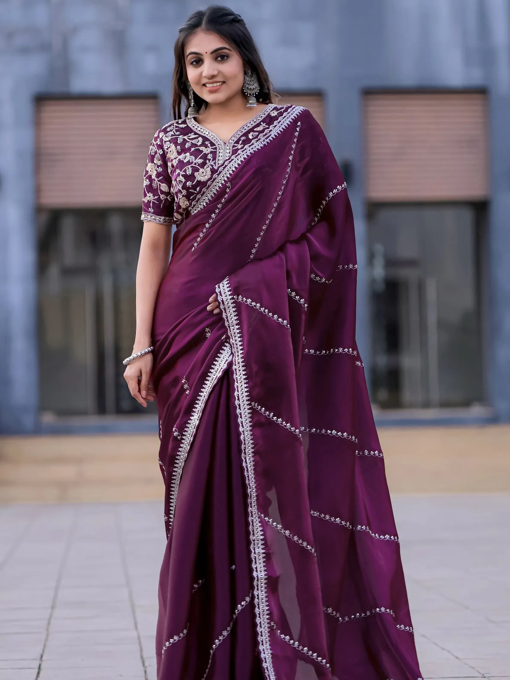 Woman wearing a purple saree with white patterns in an outdoor setting